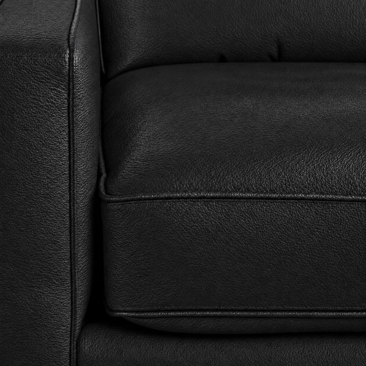 Close-up of the City Leather Chair - Black showing the leather grain, piped seat cushion and matching upholstered arm