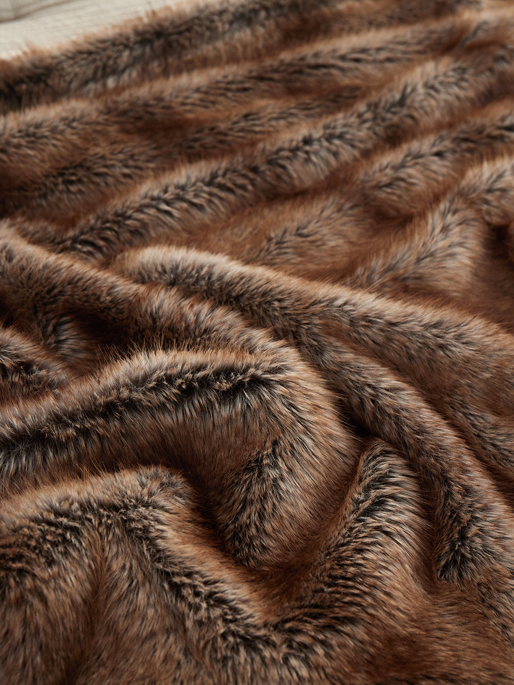 Close-up of The Great Indoors light brown faux fur throw showing plush striped pile and soft texture.
