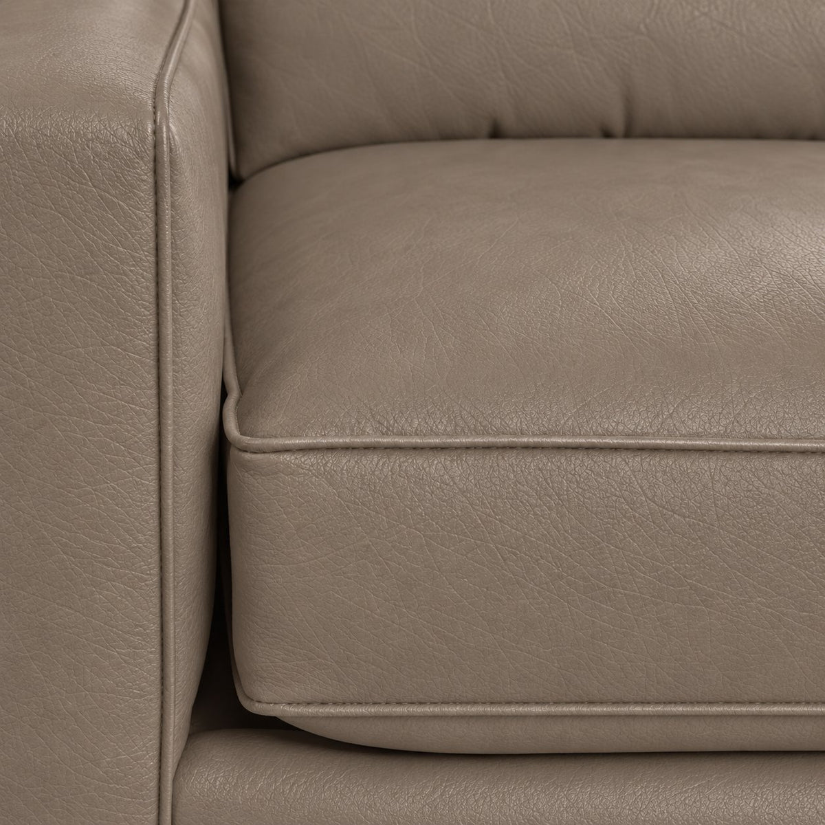 Close-up of the City Leather Loveseat - Stone showing the leather grain, piped seat cushion and matching upholstered arm