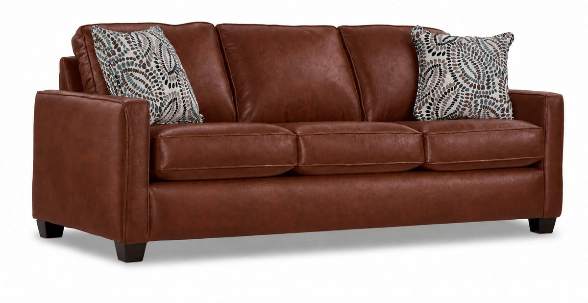 City Leather Sofa - Brown in a three-quarter view with three seat cushions, patterned accent pillows and dark wood legs