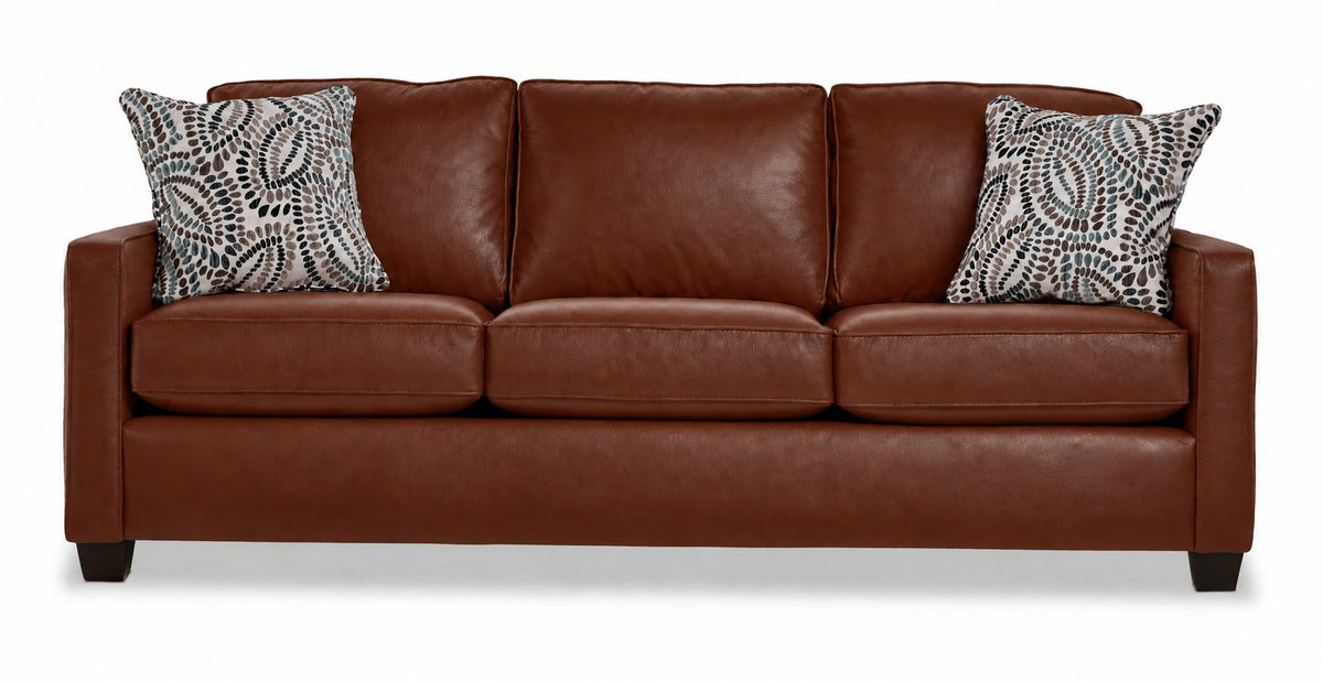City Leather Sofa - Brown front view with three cushioned seats and backs, slim track arms, dark wood legs and two patterned accent pillows