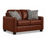 City Leather Loveseat - Brown in a three-quarter view with two cushioned seats, slim track arms, dark wood legs and two patterned accent pillows